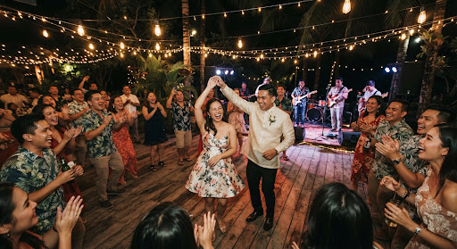 Guests dancing under string lights at an evening reception.